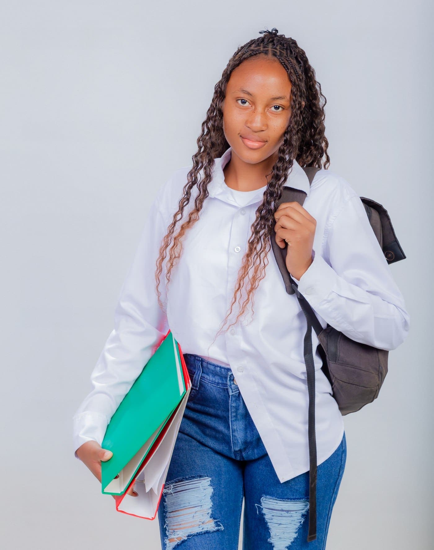 An Epiphany University Zambia student carrying folders and a backpack